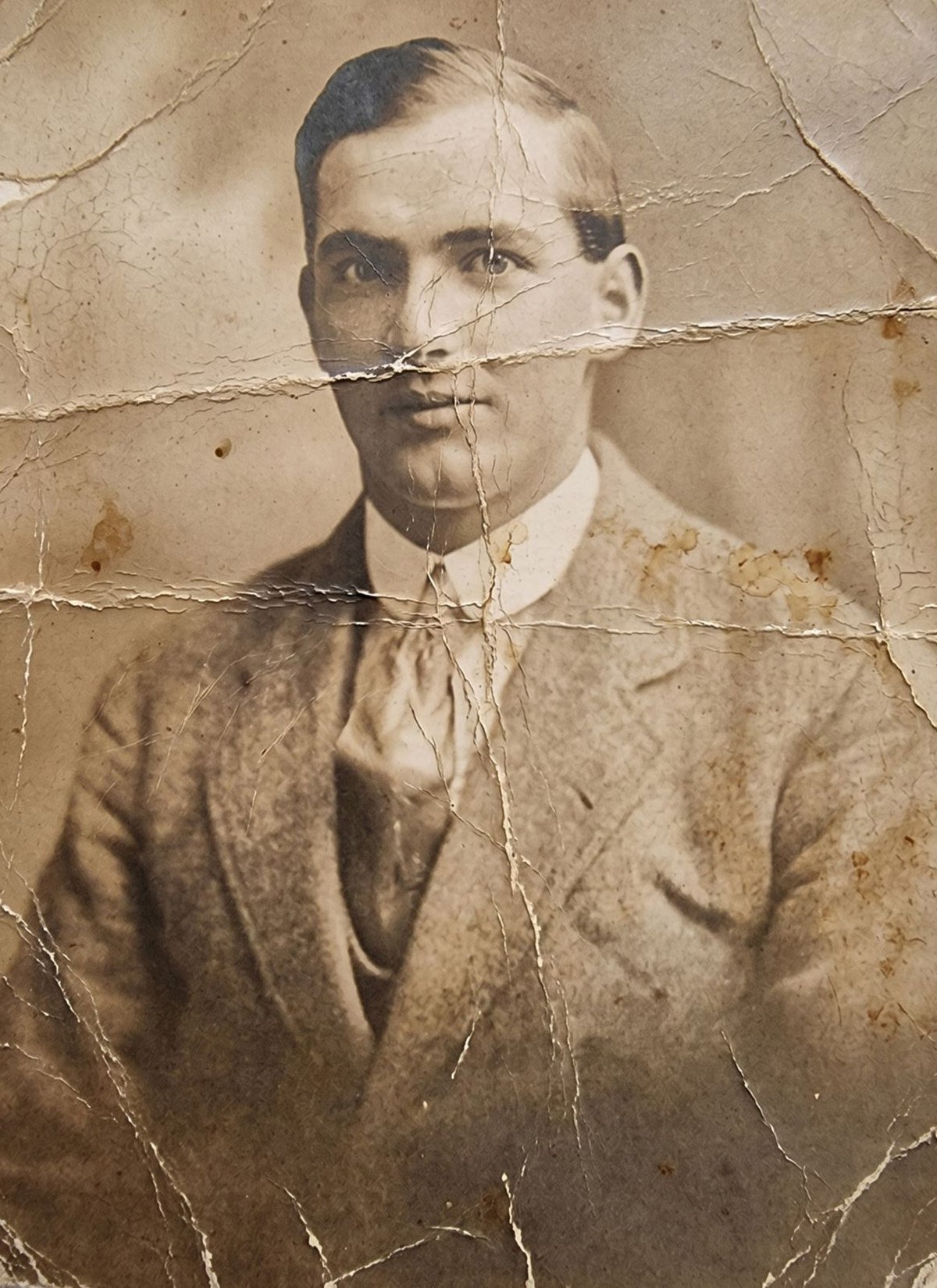Before photo restoration showing a damaged portrait with heavy creases